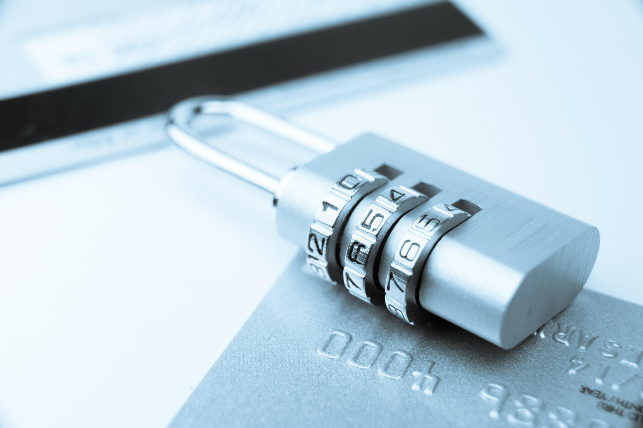 A close-up image of a combination padlock resting on a credit card, symbolizing financial security and data protection, with a cool blue tone enhancing the theme of trust and technology.