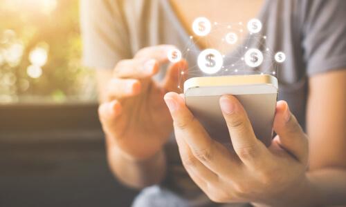 Closeup of woman on mobile device with dollar signs. Concept of ACH Transfers.