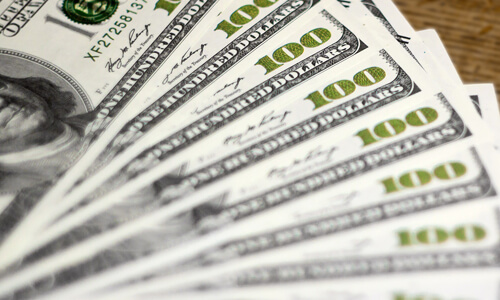 A stack of hundred dollars bills on a table.