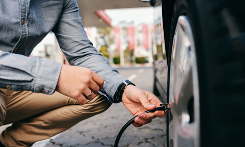 Man inflating his car tire.