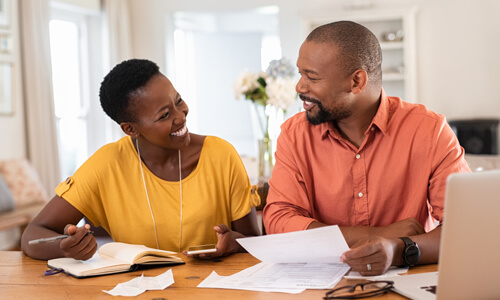 Man and woman seated together reviewing their finances.
