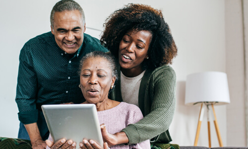 Older couple helping mother on computer, protecting her from fraud.