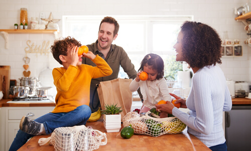 Happy family in kitchen unloading groceries.