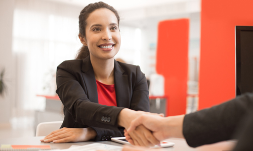 Woman on job interview shaking the hand of the job interviewer.