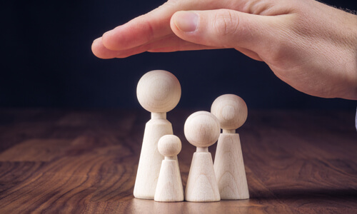Conceptual image of hand protecting family, illustrating life insurance