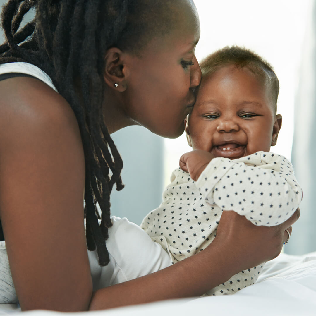 Mother kissing newborn baby.
