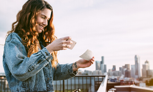 Smiling woman taking a picture of her check with her cellphone.