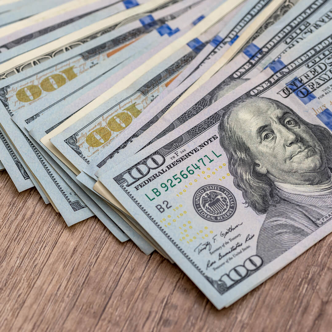 Hundred dollar bills on wooden table.