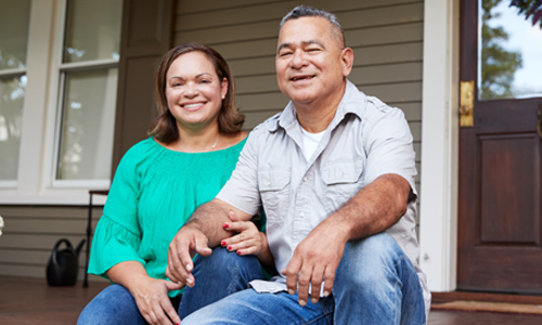 Couple seated on their front porch, smiling.