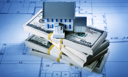 Model home sitting on top of a stack of money.