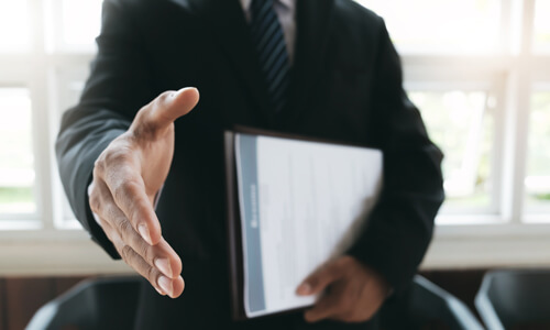 Employer holding resume and extending hand as if to welcome a new hire to a new job.