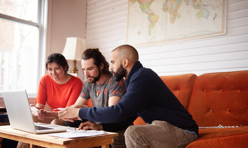 Roommates sit on couch going over rent expenses.