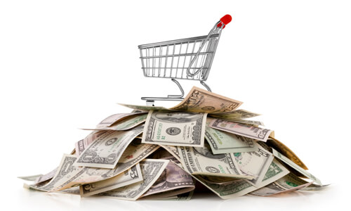 Grocery shopping cart on top of a pile of saved money.