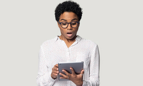 Woman looking at her computer in surprise, the victim of a scam.