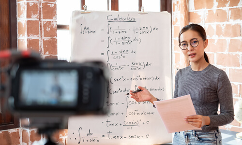 Woman standing in front of classroom, tutoring math, as a side-gig.