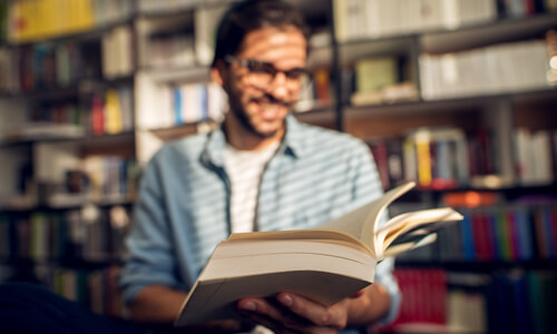 Graduate student in library, reading a book.