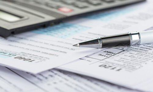 Pen sitting atop tax forms.