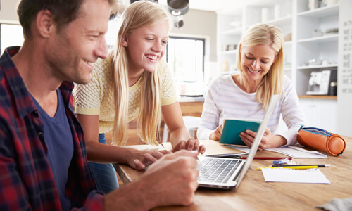 Parents sitting with teenage daughter teaching her about finances.