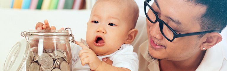 Father and new baby adding change to jar full of coins.
