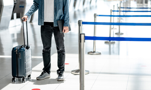 Man with travel insurance waits with suitcase for his flight.