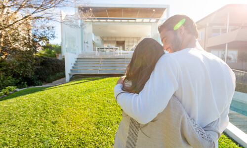 Couple who are new vacation rental owners look at their purchase and embrace.