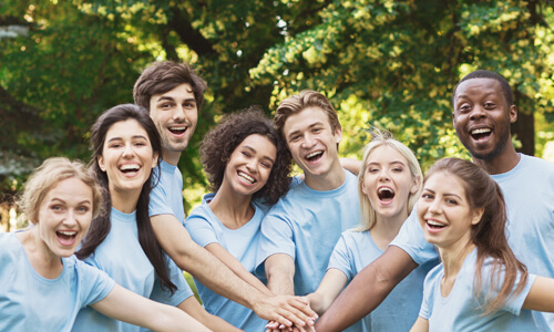 Group of young volunteers standing outside and smiling at camera.