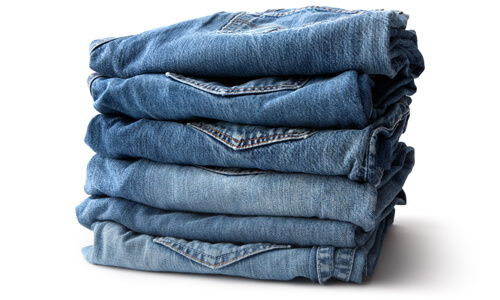 Neatly folded jeans stacked up against a white background.
