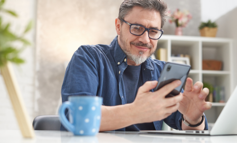 Man at a desk checking his bank account on mobile phone