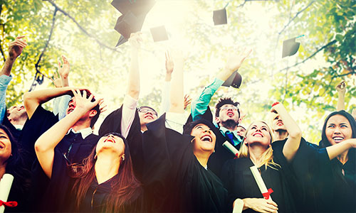 Group of college graduates throwing caps in air.