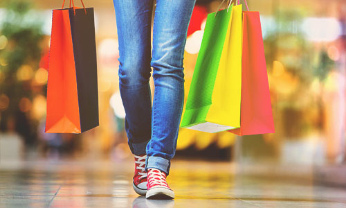 Closeup of teenager's sneakers and shopping bags at mall.