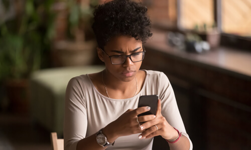 Job applicant looks at mobile phone in distress, suspecting job scam.