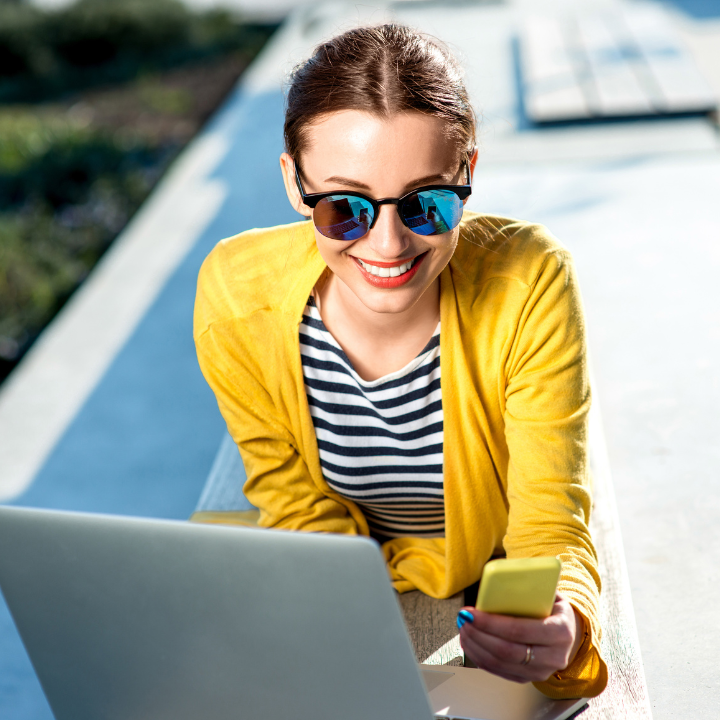 Happy woman wearing sunglasses and looking at phone