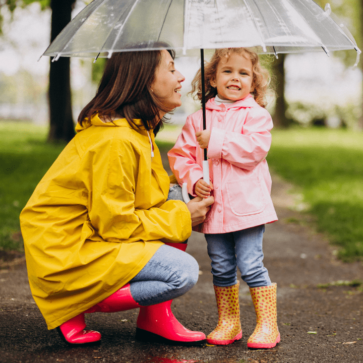 A mother and a child under an umbrella in a park.