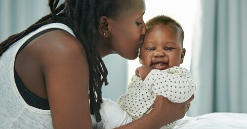 Mother kissing new infant daughter.