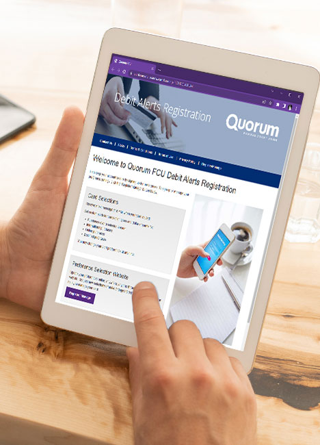 Closeup of tablet device and screen displaying Quorum’s Debit Alerts Registration page.