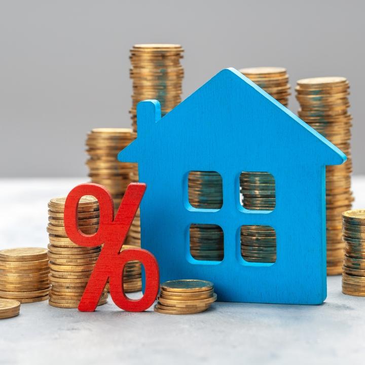 Image that illustrates the value of a home with percentage sign and house object behind a pile of dollar coins.