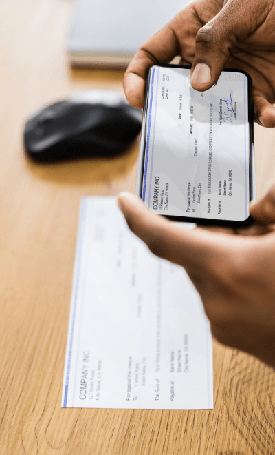 Close-up of check and phone. Man is using mobile deposit to deposit check.
