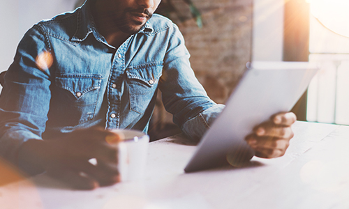 Closeup of man reviewing his tablet device, looking at his finances.