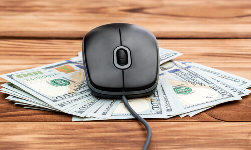 A computer mouse with hundred dollar bills underneath, illustrating the concept of wire transfers.