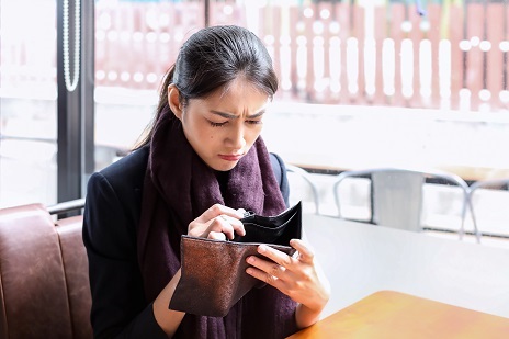 Businesswoman looks inside her empty wallet in concern, fearing identity theft.
