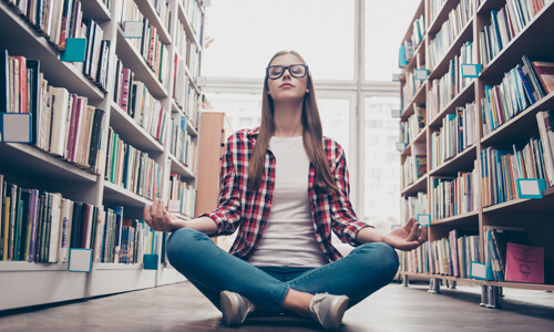 Graduate student practicing yoga in library to de-stress.