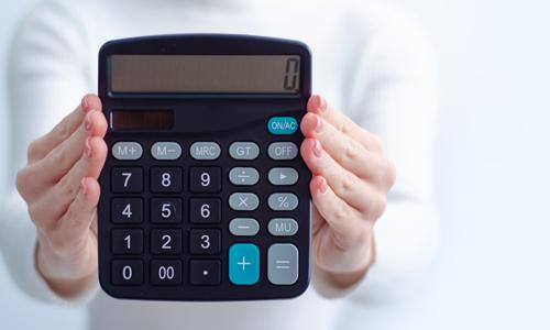 Closeup of hands holding a calculator with "0" in it, illustrating concept of a zero-based budget.